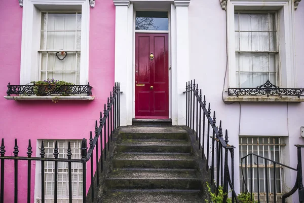 Pink and bwhite typical colorful houses and stairs with red door at Notting Hill district, near Portobello road in London, UK