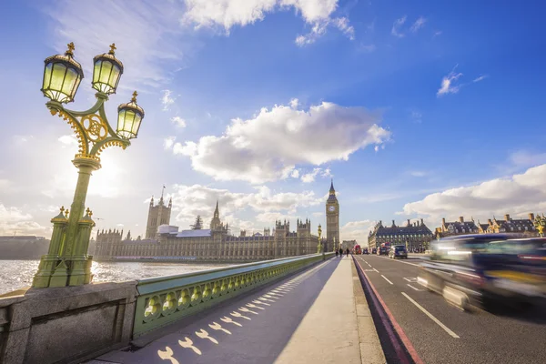 London, England - Big Ben and Houses of Parliament with traditional British black taxi on the move on Westminster Bridge