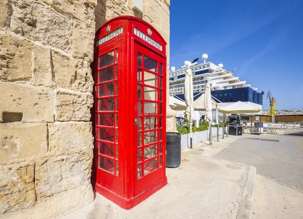 Valletta, Malta - Traditional Red Telephone box with cruise ship at background and clear blue sky