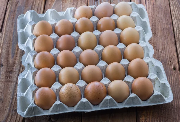 The cardboard egg tray with brown chicken eggs