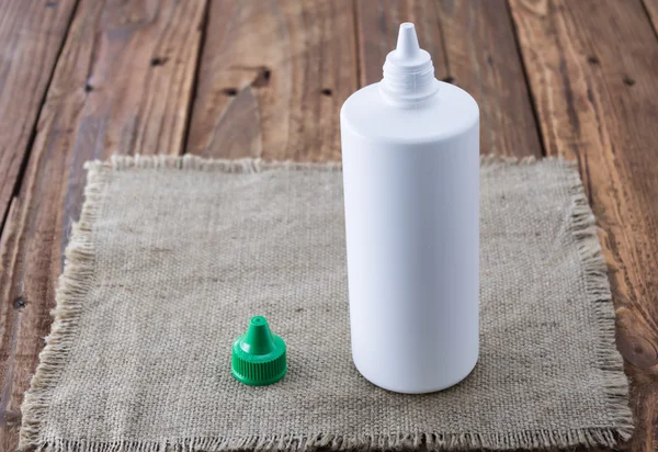 White plastic bottle mock up on wood background. Liquid lens