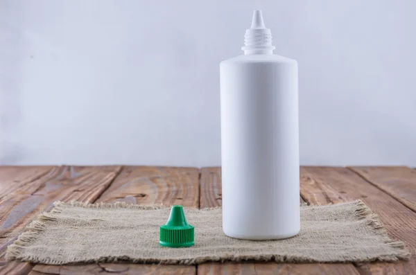 White plastic bottle mock up on wood background. Liquid lens