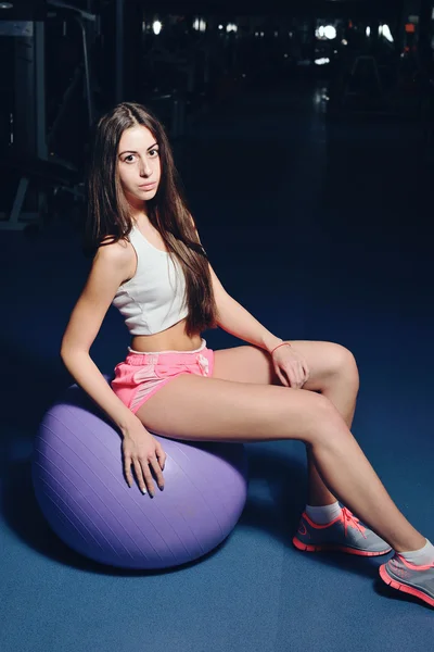 Fitness girl  posing on bench in the gym