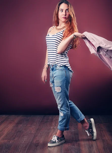 Sexy hip-hop woman in cap with long red hair. Fashion portrait of modern girl in cap