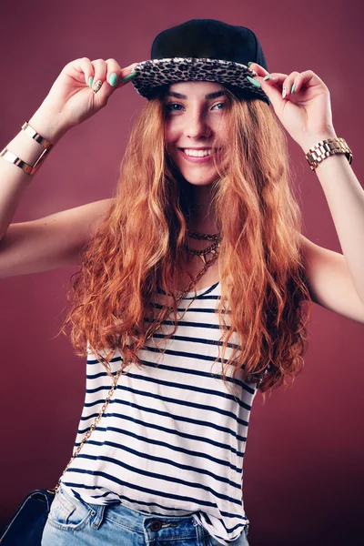 Sexy hip-hop woman in cap with long red hair. Fashion portrait of modern girl in cap