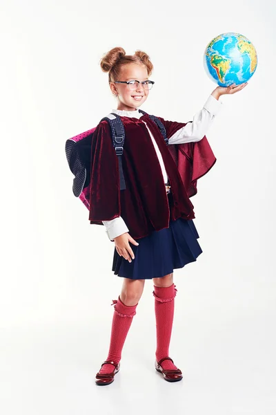 Education and school concept - little student girl studying geography with globe and book