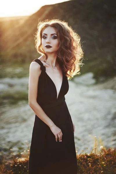 Fashion shot of the elegant young woman posing over beautiful landscape.