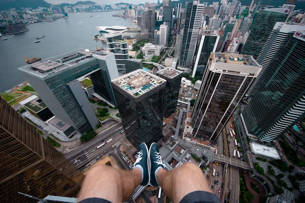 Sitting on the edge of the roof of a skyscraper in modern part of Hong Kong