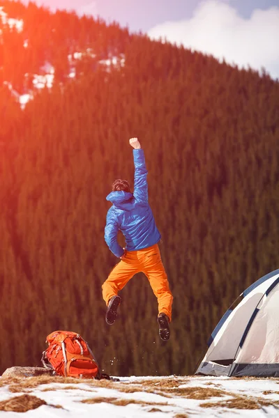 Hiker's joy jumping on mountain peak.