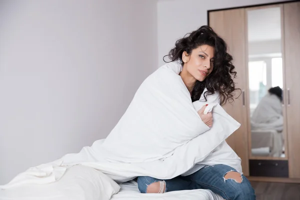 Long hair woman in blue jeans on white bed