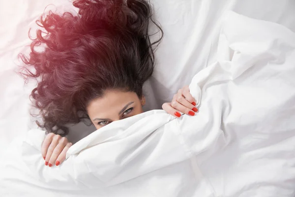 Brunette long hair woman in a bed under the duvet