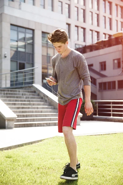 Athlete taking rest with smartphone after urban running