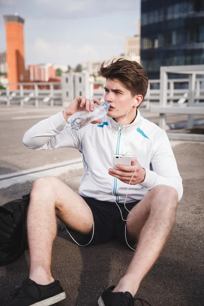 Adult male athlete drinking water after run