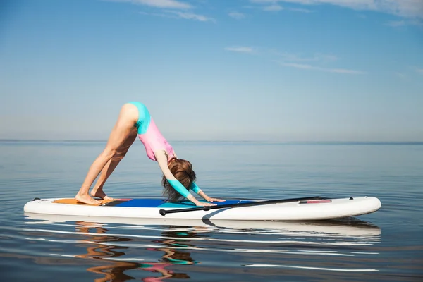 Woman doing yoga pranayam on sup board with paddle