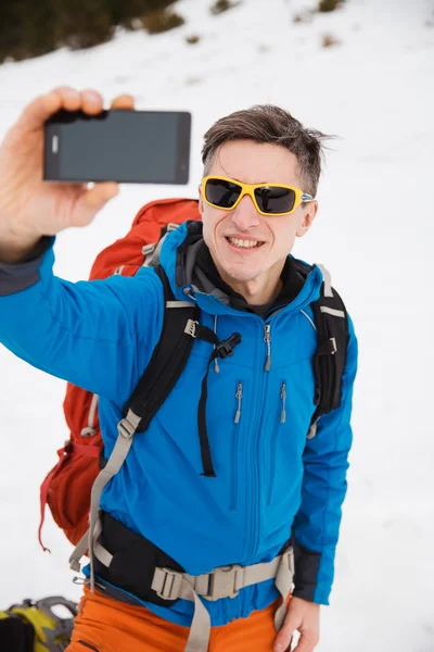 Hiker in winter mountains making selfie on smartphone