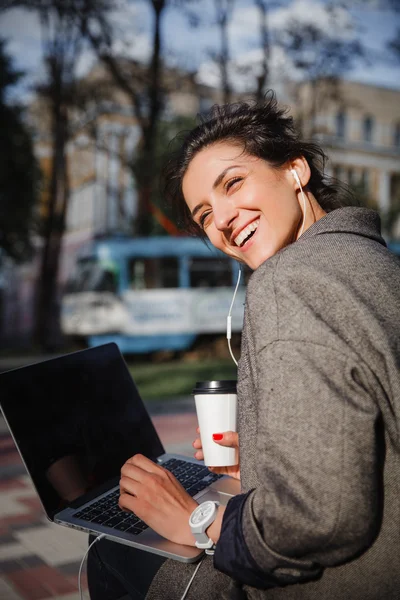 Middle aged woman with laptop and coffee in the city
