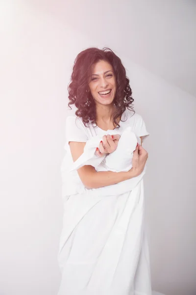 Brunette woman covered by white duvet on hite bed