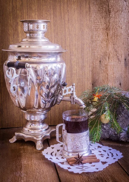 Tea in glass with coaster and russian samovar on wooden background. Home christmas decoration. Warm colors