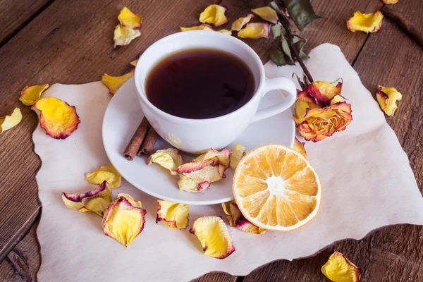 Cup of tea, dried oranges, dried rose petals on wooden background