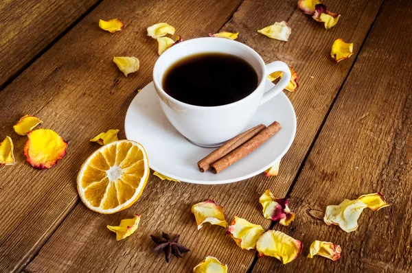 Cup of tea, dried orange, dried yellow rose petals on wooden background