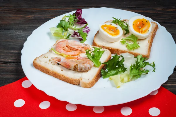Sandwiches with shrimp, egg, basil, salad, bread on wood background. Delicious cold snacks. Vegetarian meals. Healthy eating
