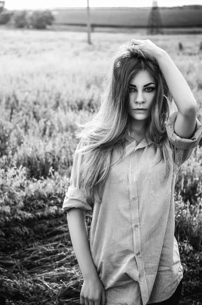 Beautiful and young girl in a man\'s shirt standing in the field