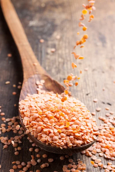 Red lentils spilling in a wooden spoon