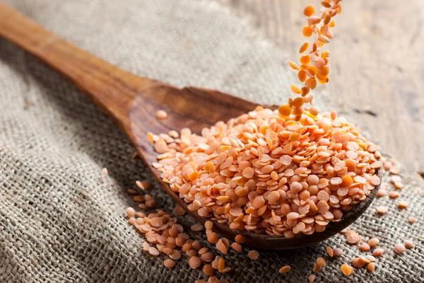 Red lentils spilling in a wooden spoon