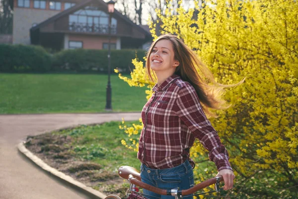 Beautiful young woman with vintage bicycle in a park