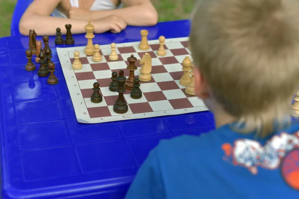 Little boy learning to play chess with a friend