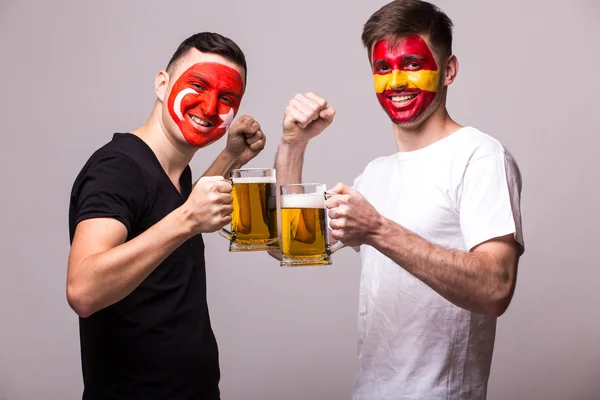 Spain and Turkey football fan drink beer on grey background.