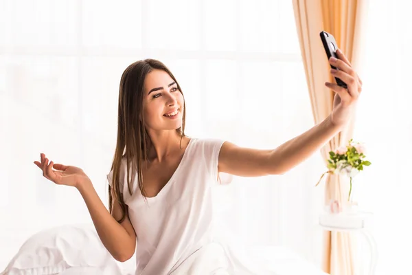 Beauty girl taking selfie from phone in the morning in bed at home