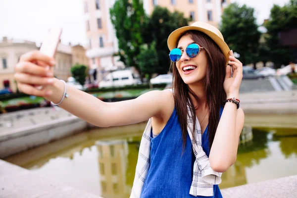 Young smiling teen happy woman making selfie on the street, glasses, traveling alone, having fun, positive mood, joy, vacation, surprised emotions.