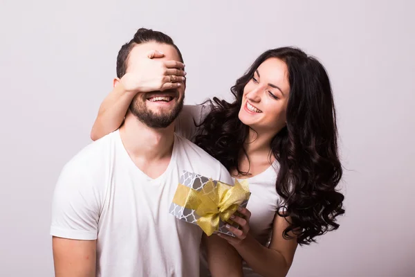 Attractive happy woman with big toothy smile holding boyfriends eyes giving him a present for Valentine\'s day