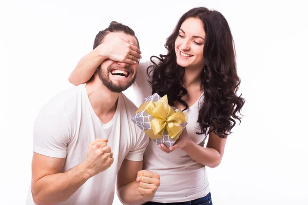 Attractive happy woman with big toothy smile holding boyfriends eyes giving him a present for Valentine\'s day