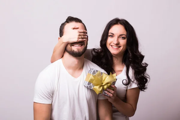 Attractive happy woman with big toothy smile holding boyfriends eyes giving him a present for Valentine\'s day