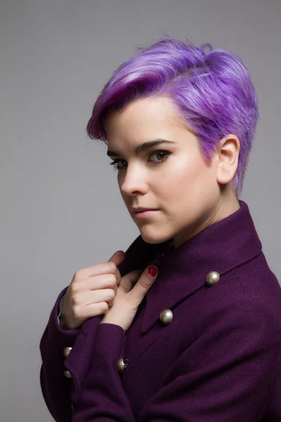 Violet-short-haired woman wearing a violet coat, looking at came