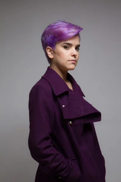 Violet-short-haired woman wearing a violet coat, looking at came