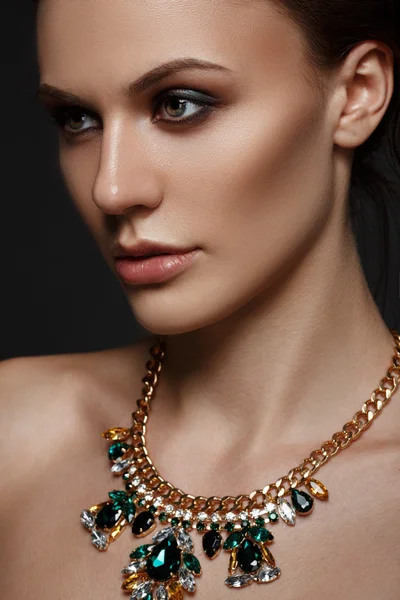 Elegant young woman with evening smart make up and sparkling necklace jewelry on her neck. Gorgeous woman face.