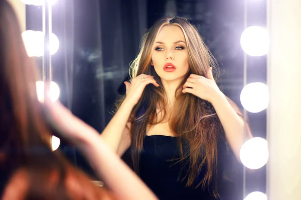 Young caucasian woman looking into makeup mirror at herself and enjoying her time.