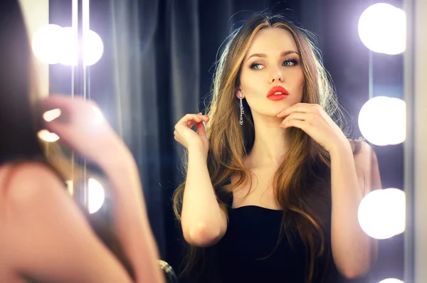 Young caucasian woman looking into makeup mirror at herself and enjoying her time.