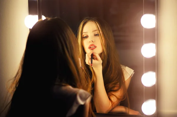 Sexy woman looking into a mirror at herself and use cosmetic