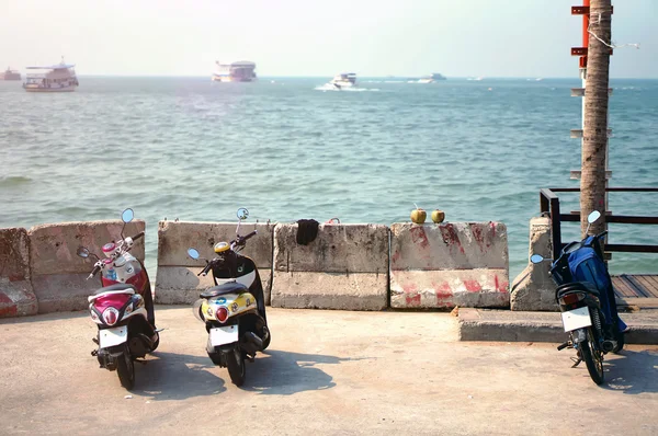 Scooters parked on parking with sea bay