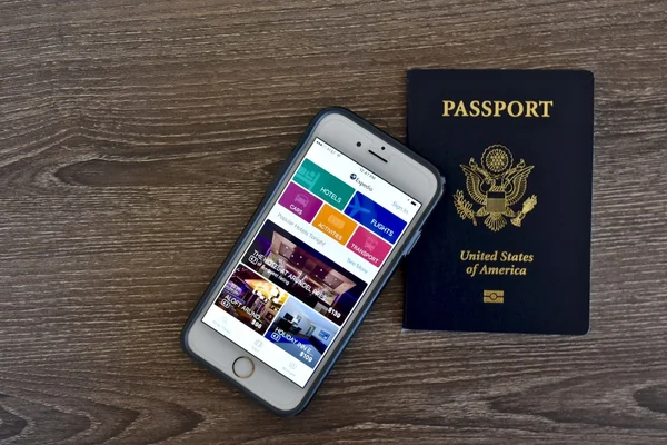 Apple iPhone displaying the Expedia application on screen while next to an American passport
