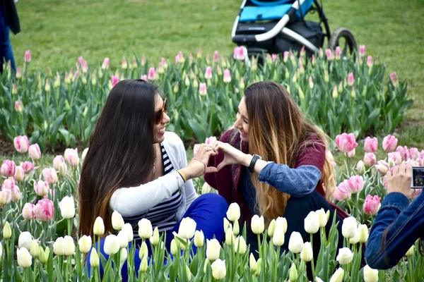 Two girls posing or pictures in a flower garden