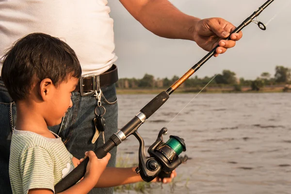 Son and dad fishing at river