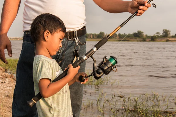 Son and dad fishing at river