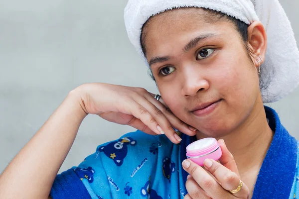 Woman applying moisturizer cream on her pretty face