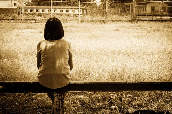 Sad asian girl sitting alone  near railway Stations ,vintage ton