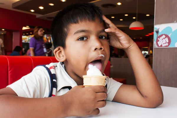 Kid boy hand holding a dripping ice cream cone in shop